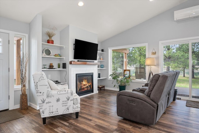 living area with a wall unit AC, wood finished floors, baseboards, vaulted ceiling, and a tiled fireplace