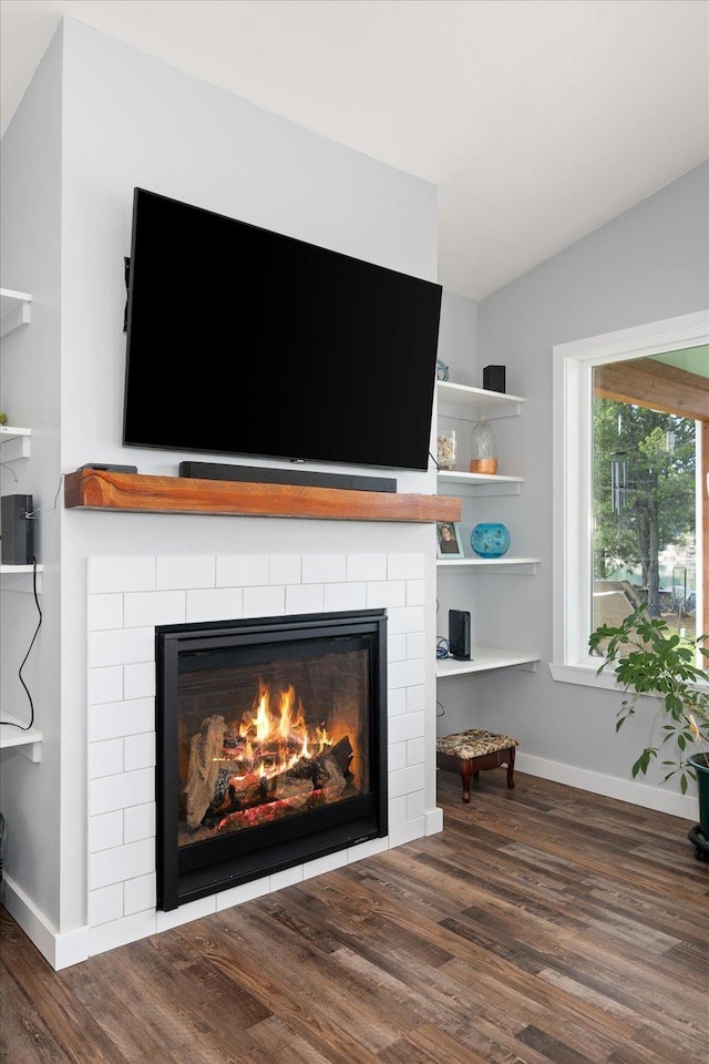 interior details with wood finished floors, a glass covered fireplace, and baseboards