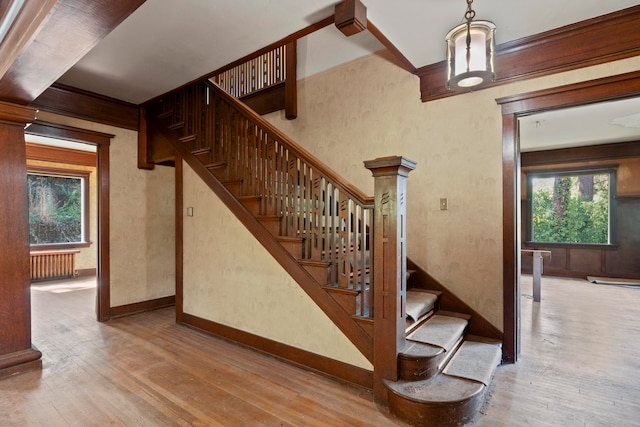 staircase with ornamental molding, radiator, and hardwood / wood-style flooring