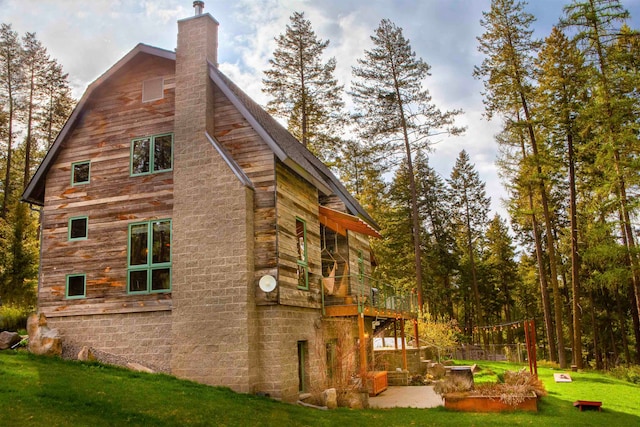 view of home's exterior with a deck, a yard, a chimney, and a patio area