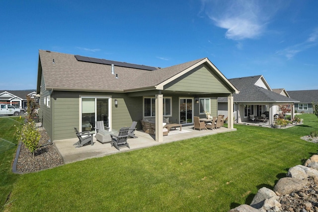 back of property featuring solar panels, a lawn, and a patio