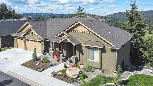 craftsman-style home with a garage, driveway, roof with shingles, and central AC