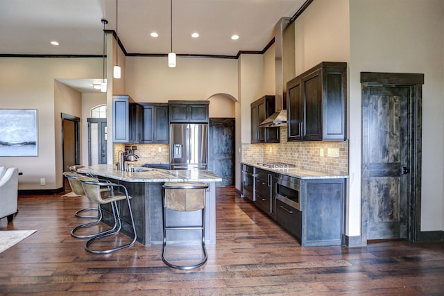 kitchen featuring stainless steel appliances, a sink, a kitchen breakfast bar, light stone countertops, and dark wood finished floors