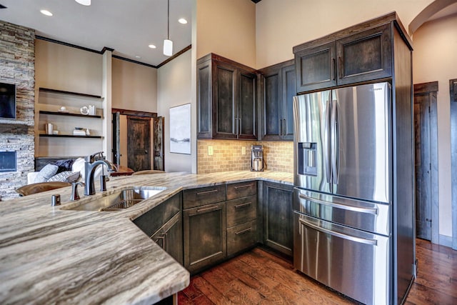 kitchen featuring dark wood finished floors, light stone counters, dark brown cabinets, stainless steel refrigerator with ice dispenser, and a sink