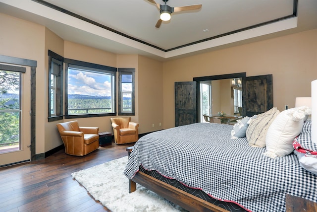 bedroom with a ceiling fan, a raised ceiling, hardwood / wood-style flooring, and baseboards