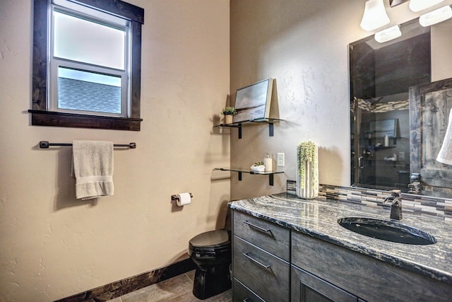 bathroom featuring toilet, an enclosed shower, baseboards, and vanity