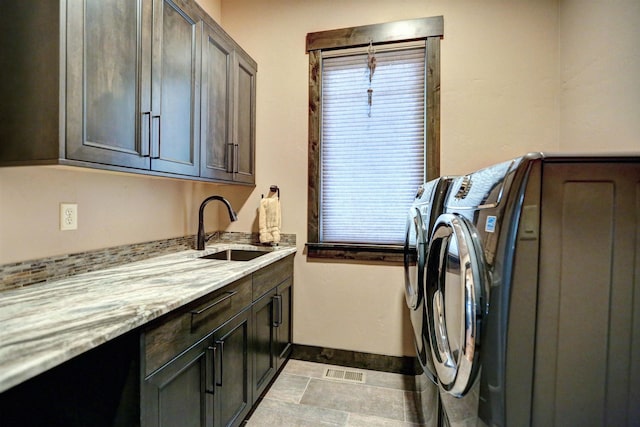 washroom with cabinet space, baseboards, visible vents, washer and clothes dryer, and a sink