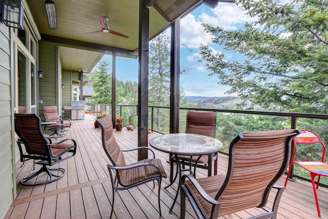 wooden terrace with grilling area, a ceiling fan, and outdoor dining space