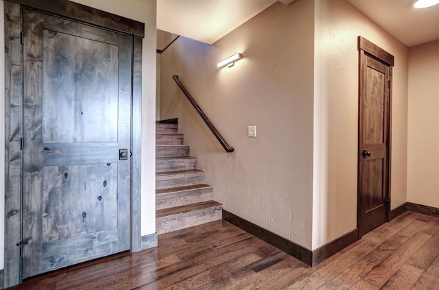 staircase featuring baseboards and wood finished floors