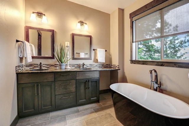 full bath with double vanity, a freestanding tub, and a sink