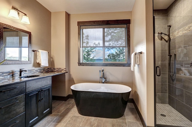 bathroom with a stall shower, baseboards, a soaking tub, and vanity