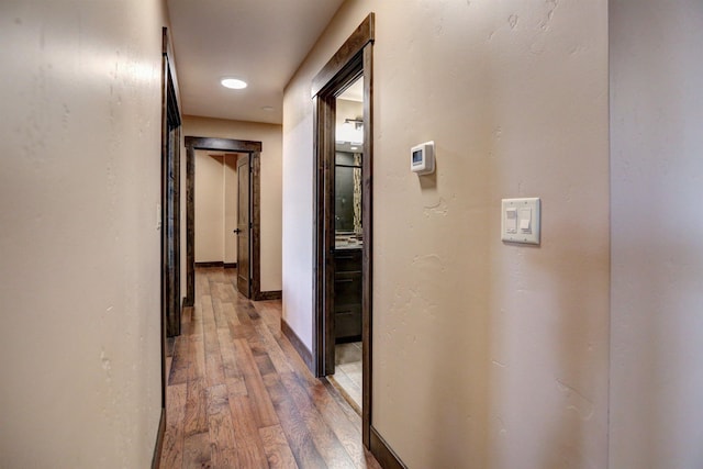 hallway featuring light wood-type flooring and baseboards