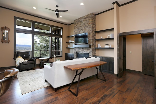 living area featuring dark wood-type flooring, recessed lighting, crown molding, and a fireplace