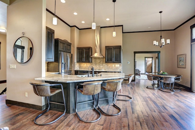 kitchen featuring decorative backsplash, stainless steel fridge with ice dispenser, ornamental molding, a peninsula, and a sink