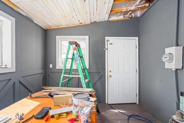 interior space featuring a textured wall, a decorative wall, wood ceiling, wainscoting, and vaulted ceiling