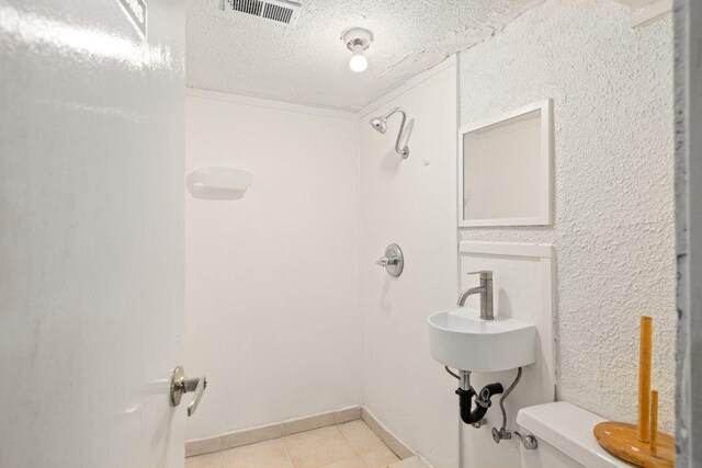 bathroom with visible vents, toilet, a textured ceiling, tile patterned flooring, and baseboards