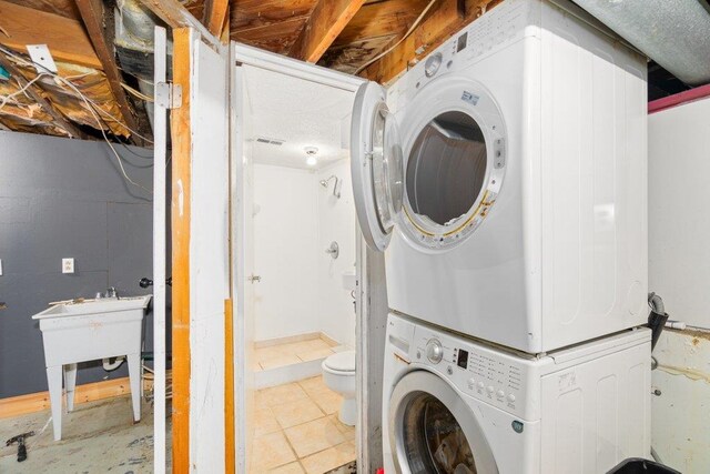 laundry area featuring laundry area, tile patterned flooring, and stacked washer / dryer