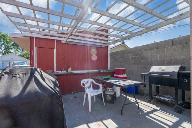 view of patio with outdoor dining area, area for grilling, fence, an outdoor structure, and a pergola