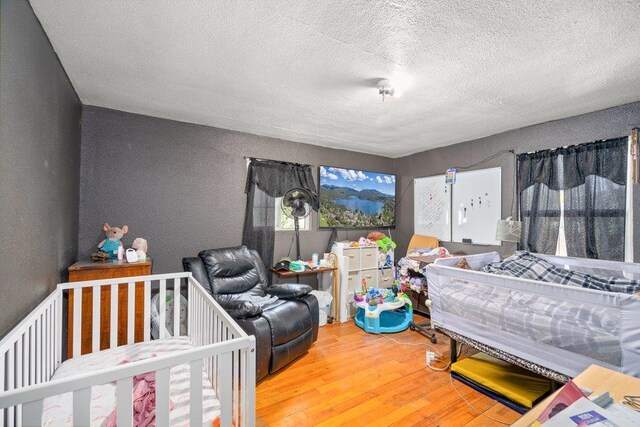 bedroom with a textured ceiling and wood finished floors