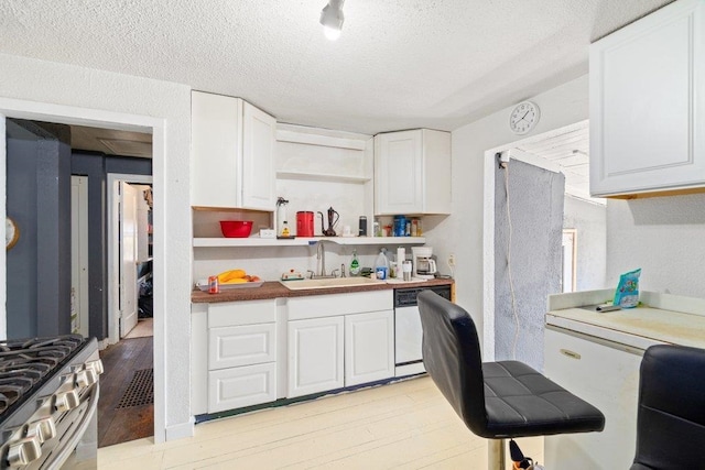 kitchen with dishwashing machine, a sink, white cabinetry, open shelves, and light wood finished floors