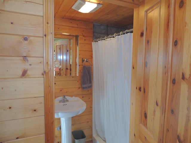 bathroom with curtained shower, wooden ceiling, and wooden walls