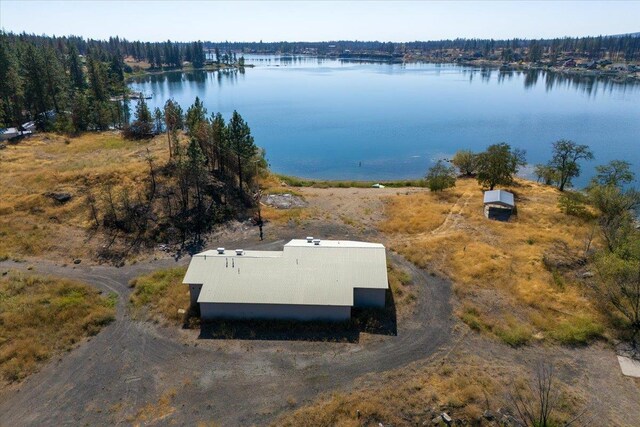 drone / aerial view featuring a wooded view and a water view