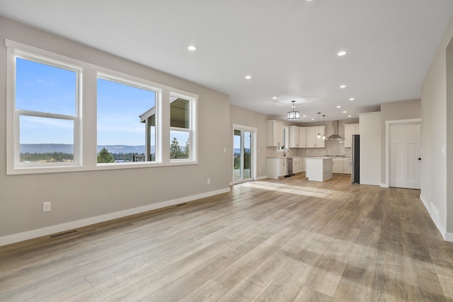 unfurnished living room with light hardwood / wood-style floors, a mountain view, and plenty of natural light