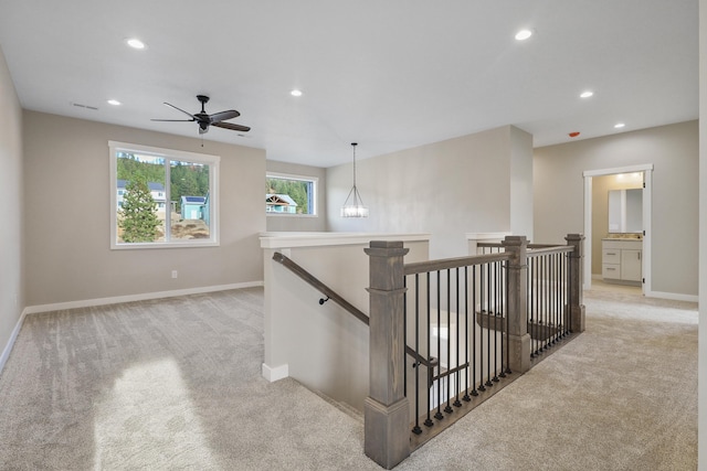 hall with a chandelier and light colored carpet