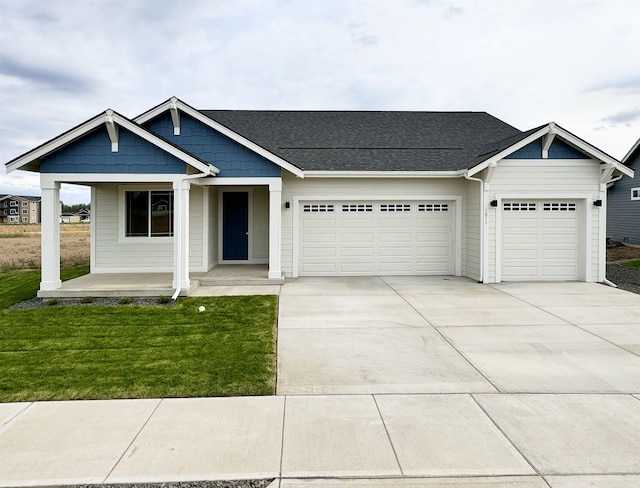 view of front facade featuring driveway, an attached garage, a front yard, and a shingled roof