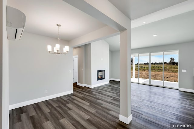 5871 S Sherri Lea Rd, Spokane, WA 99224 - unfurnished living room featuring a wall unit AC, baseboards, dark wood finished floors, a glass covered fireplace, and a notable chandelier
