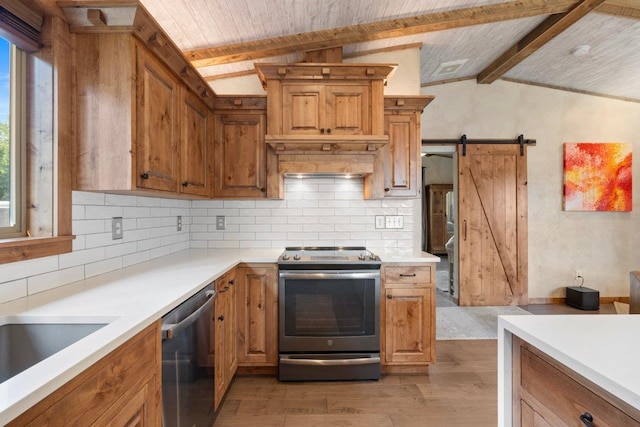 kitchen featuring light wood-type flooring, a healthy amount of sunlight, vaulted ceiling with beams, appliances with stainless steel finishes, and a barn door