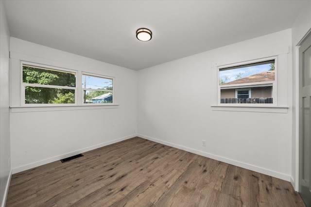 unfurnished room with a healthy amount of sunlight and dark wood-type flooring