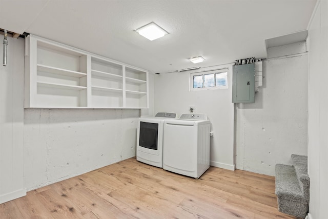 laundry area featuring electric panel, separate washer and dryer, and light hardwood / wood-style flooring