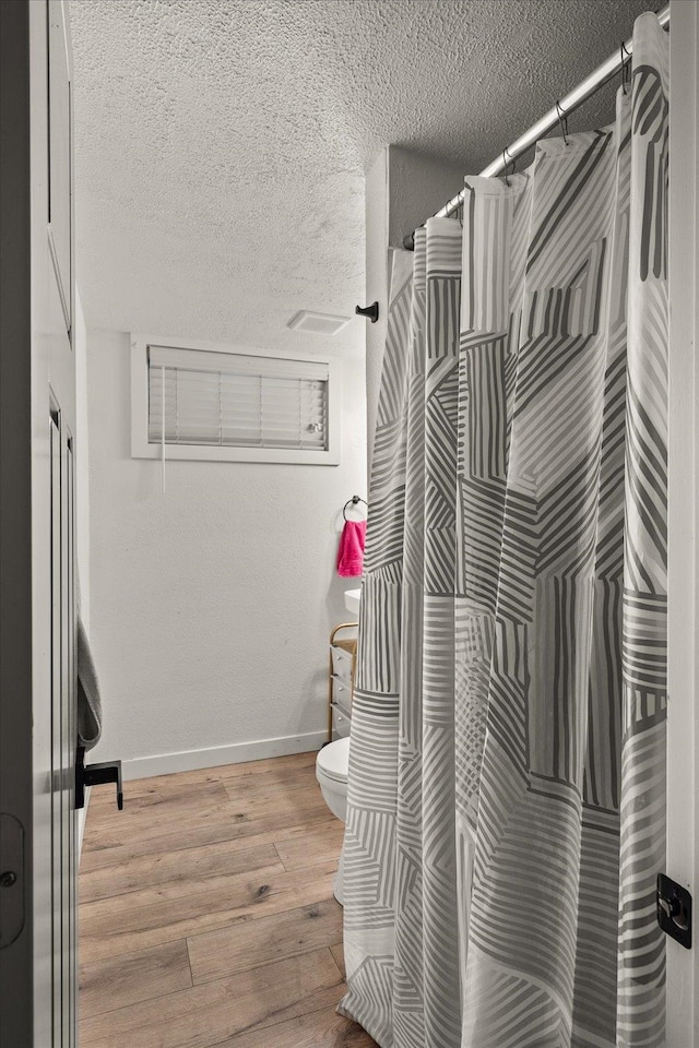 bathroom featuring toilet, a textured ceiling, and hardwood / wood-style flooring