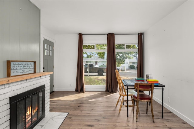 dining area featuring hardwood / wood-style flooring and a brick fireplace