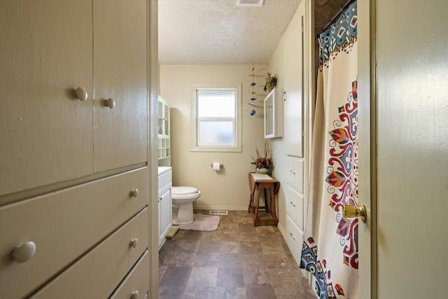 bathroom featuring vanity, toilet, a shower with curtain, and a textured ceiling