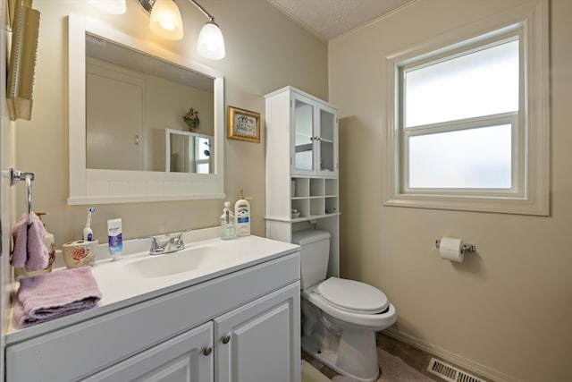 bathroom with vanity, toilet, plenty of natural light, and a textured ceiling