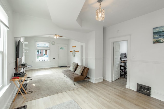 living area featuring light hardwood / wood-style flooring and ceiling fan with notable chandelier