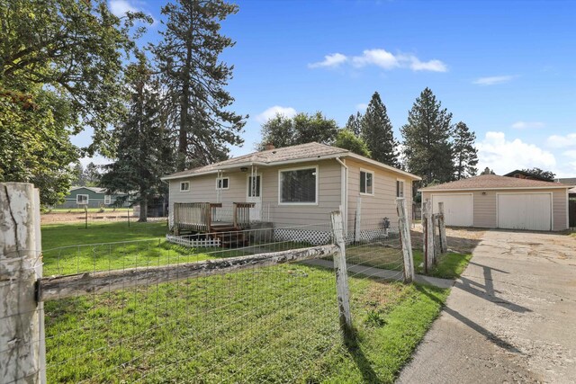 view of front of property with a front yard, a garage, an outdoor structure, and a wooden deck