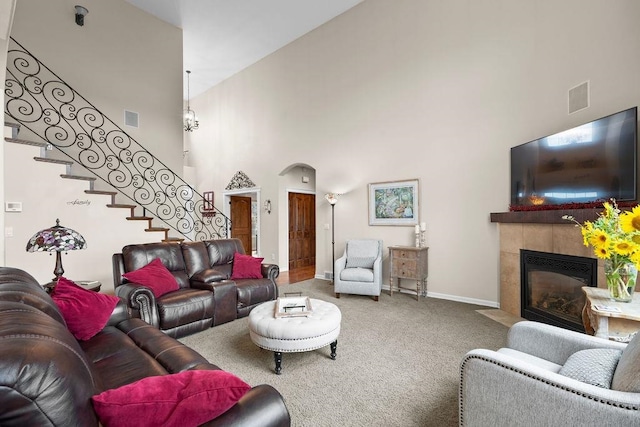 carpeted living room featuring a fireplace and high vaulted ceiling