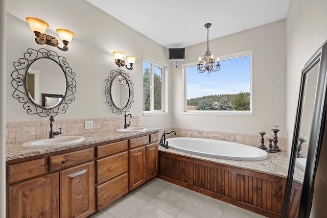 bathroom with vanity, an inviting chandelier, tile patterned floors, and a washtub