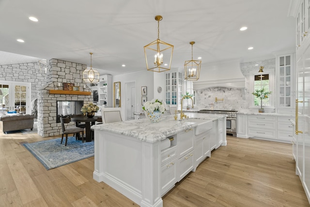 kitchen with white cabinets, a center island, light wood-type flooring, custom exhaust hood, and pendant lighting