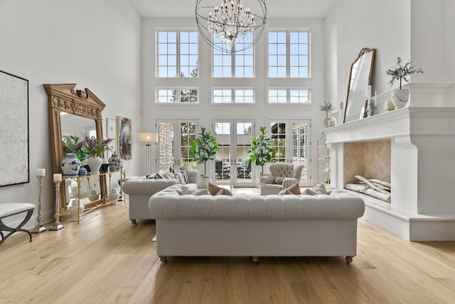 living room with a high end fireplace, plenty of natural light, a notable chandelier, and light hardwood / wood-style floors