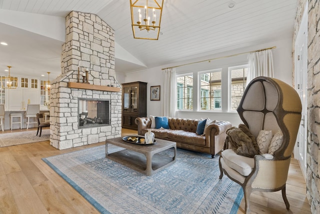 living room with vaulted ceiling, an inviting chandelier, a stone fireplace, light hardwood / wood-style floors, and wood ceiling