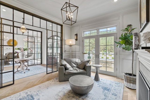 living area featuring light parquet floors, ornamental molding, a chandelier, and french doors