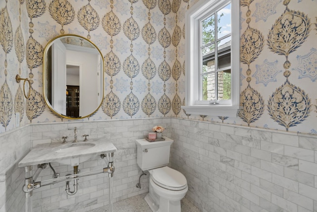 bathroom with tile walls, toilet, sink, and tile patterned floors