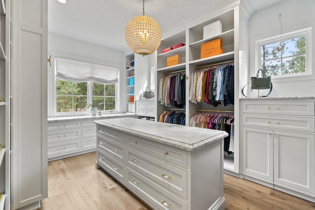 walk in closet with a chandelier and light hardwood / wood-style floors