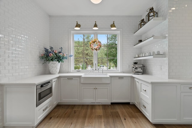 kitchen featuring light wood-type flooring, oven, sink, and white cabinets