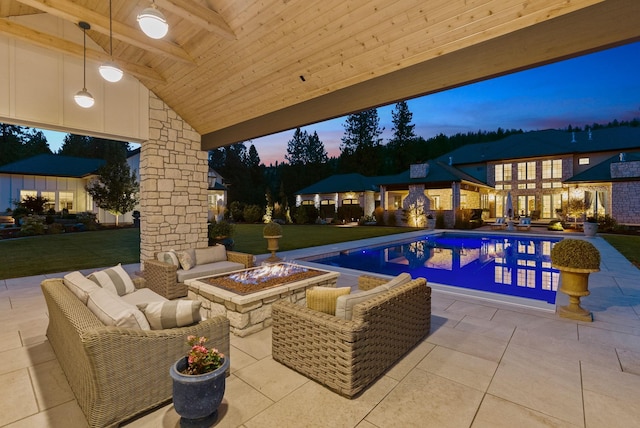 pool at dusk with a lawn, an outdoor living space with a fire pit, and a patio