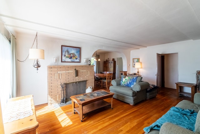 living room with a brick fireplace and hardwood / wood-style flooring